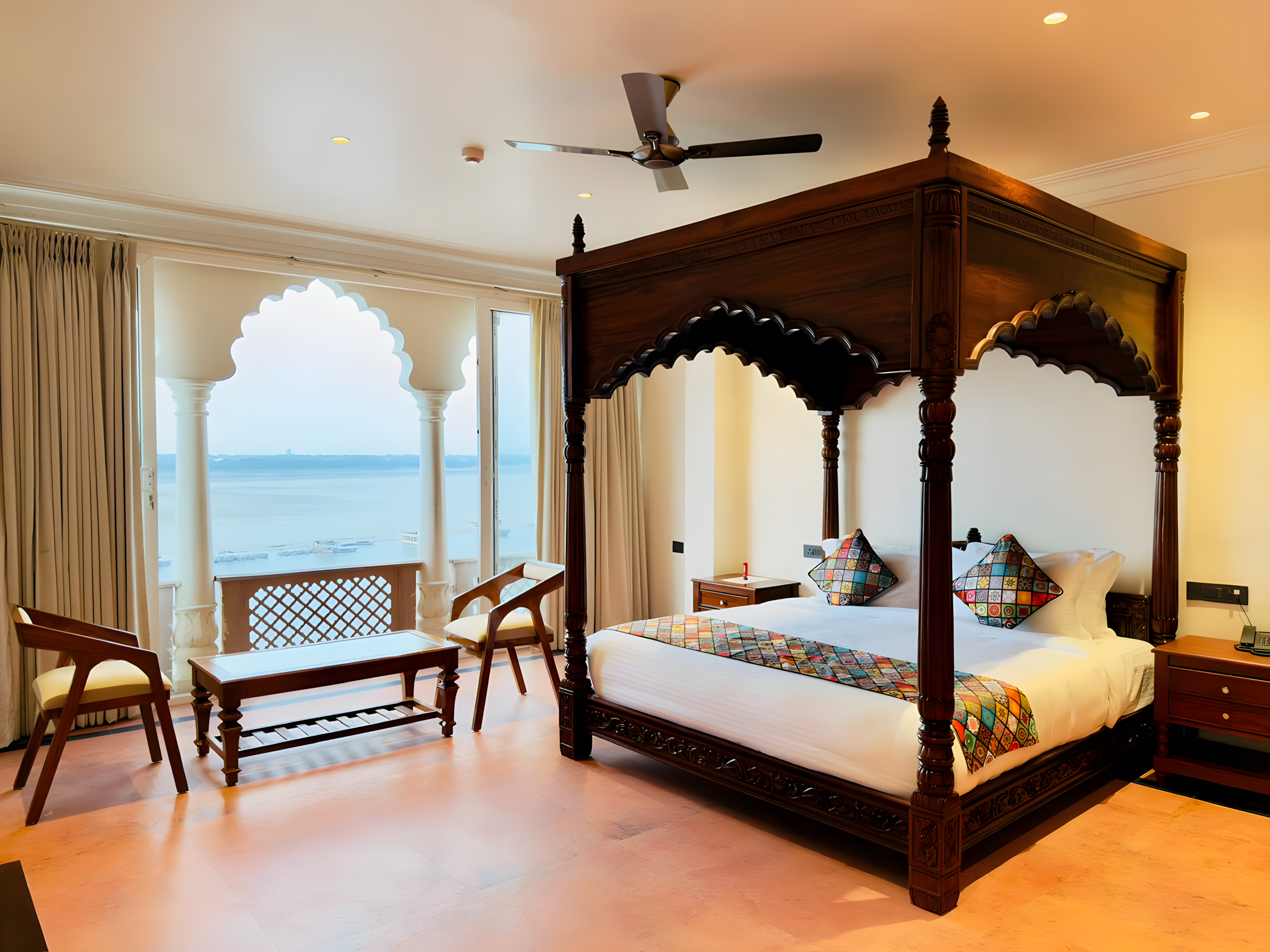 Kaashi Suite at Maharana Mahal heritage hotel Varanasi — carved four-poster teak bed with Banarasi patchwork pillows, private colonnade balcony with morning Ganga river view — boutique palace hotel Banaras