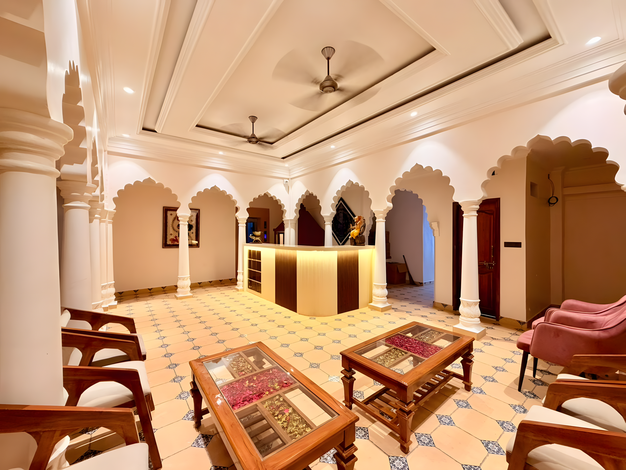 Heritage hotel lobby at Maharana Mahal Varanasi — carved white Mughal colonnade, traditional teak furniture, Rajasthani mosaic tile floor — boutique palace hotel near Dashashwamedh Ghat