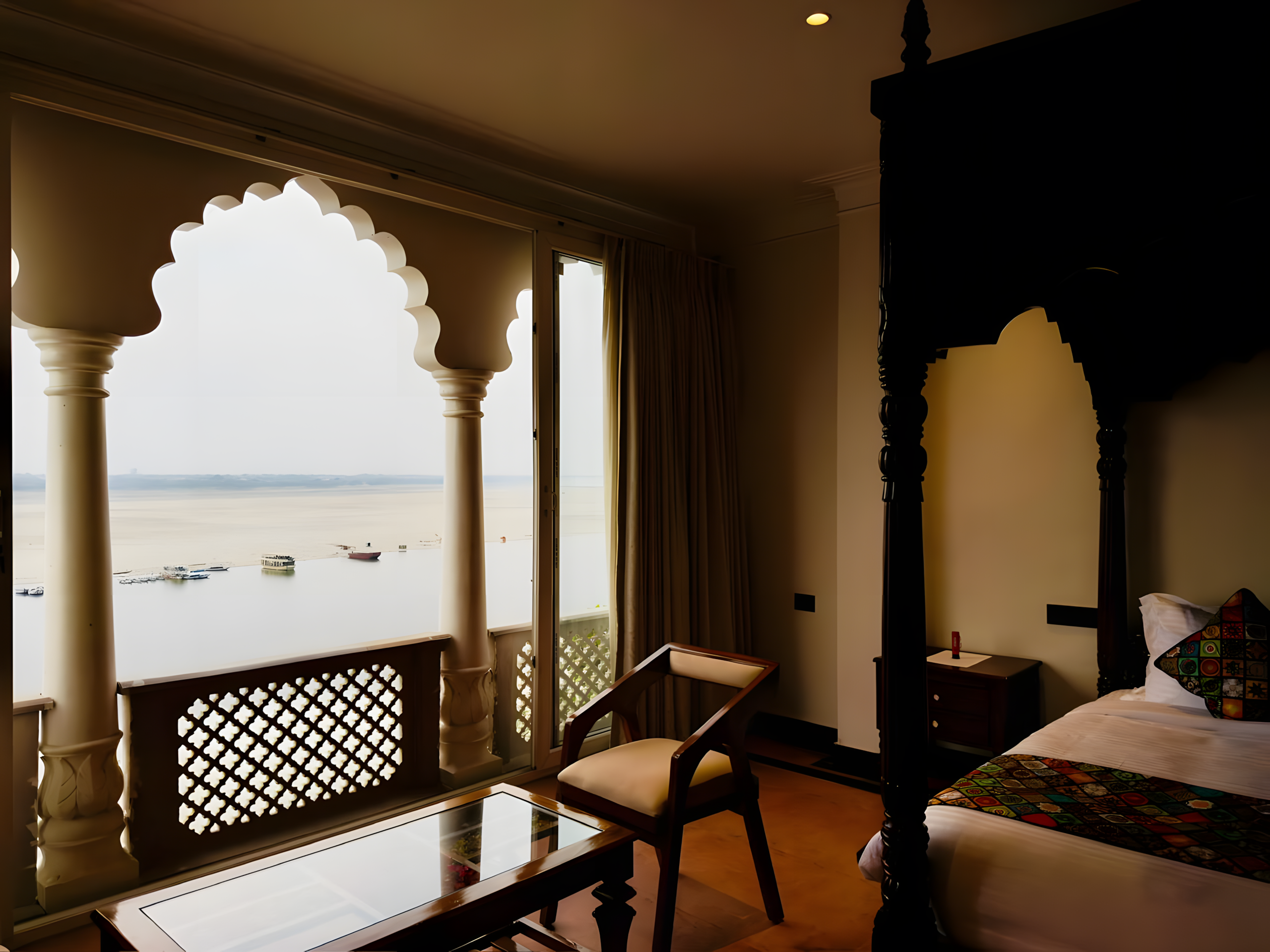 Wide-angle hotel lobby at Maharana Mahal heritage hotel Varanasi — arched white Mughal colonnade, warm ambient lighting, illuminated reception desk, traditional wooden seating — luxury palace hotel near Kashi Vishwanath Temple