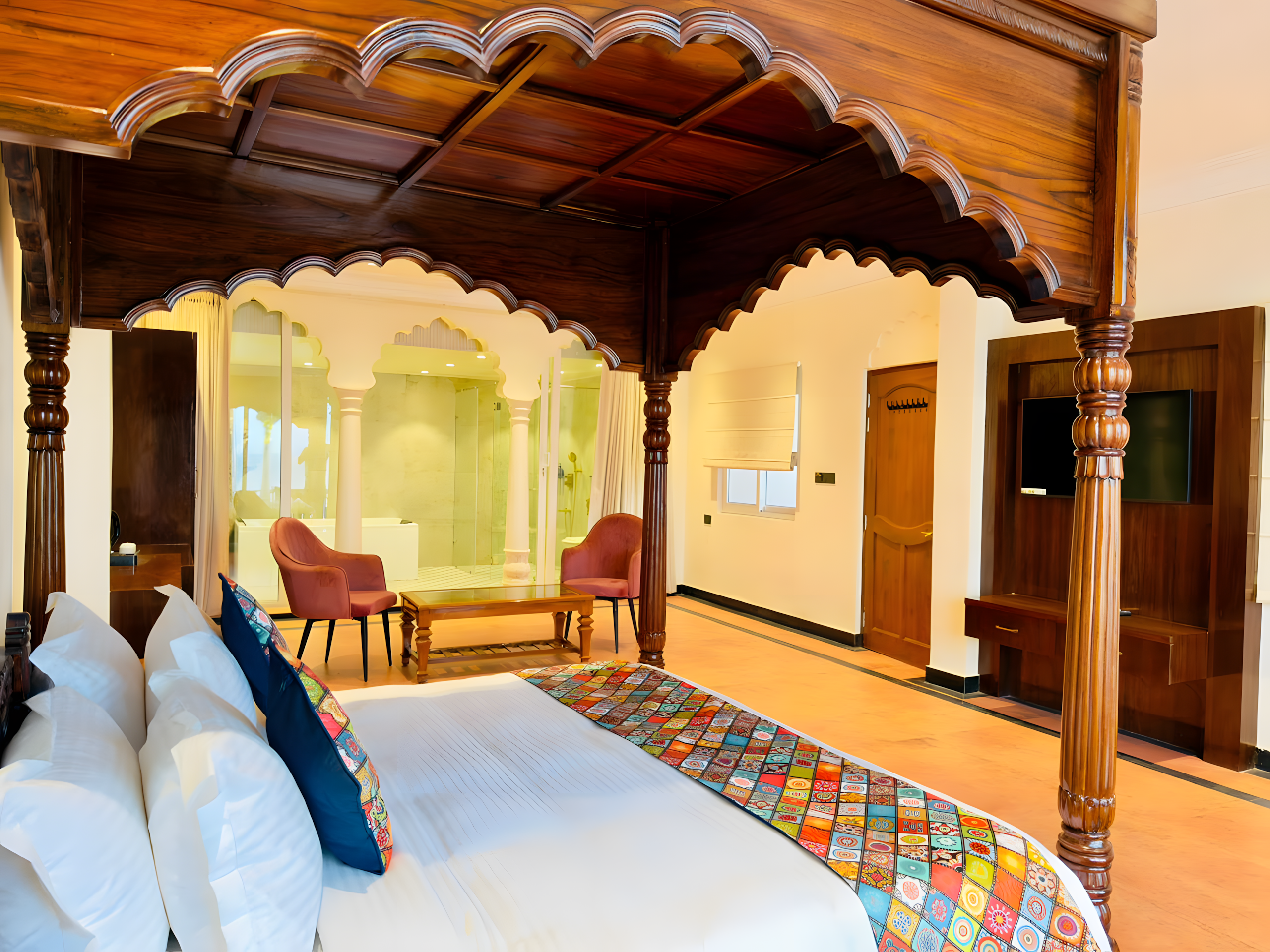 Ganga Darshan Suite at Maharana Mahal Varanasi — carved Mughal arch four-poster king bed, colorful Banarasi patchwork runner, open glass anteroom with live tree-trunk bathtub — heritage palace hotel Ganges