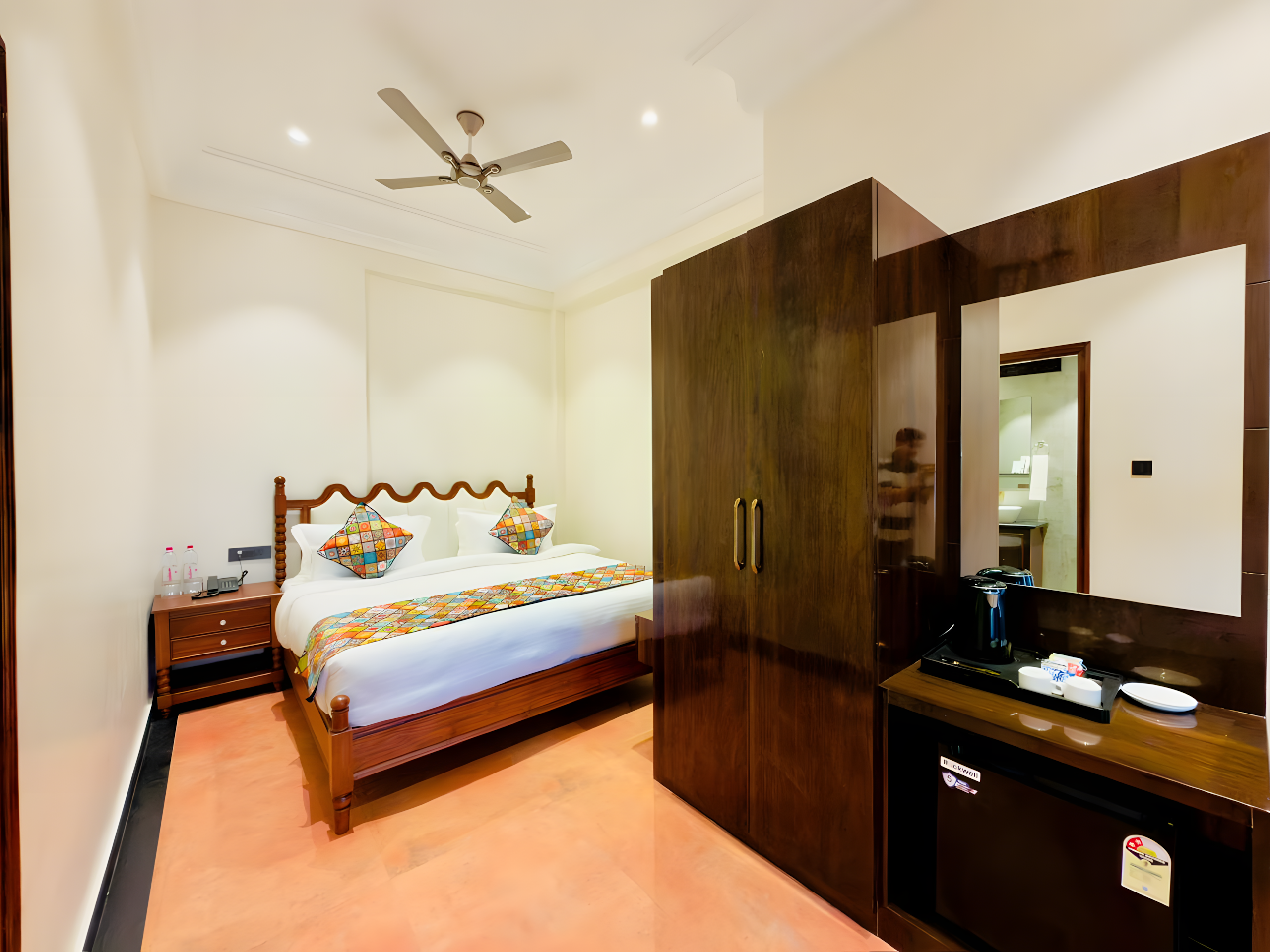 Benaras Heritage Room at Maharana Mahal hotel Varanasi — double bed with vibrant hand-stitched Banarasi patchwork bedding, teak wardrobe with mirror — boutique heritage room in 17th-century palace Kashi